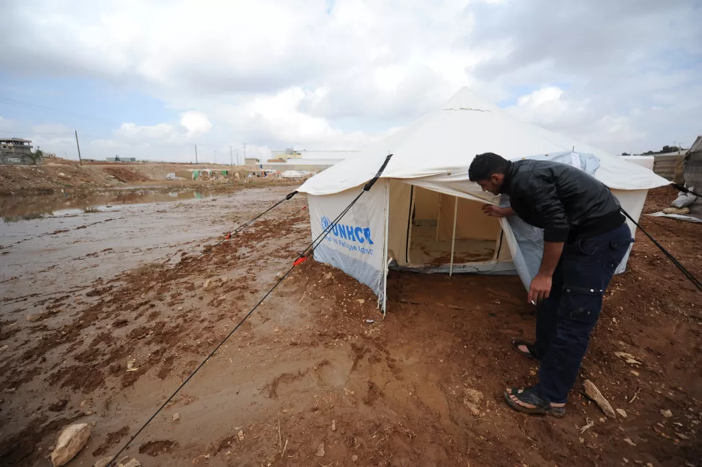 A man looks into a tent next to flood water