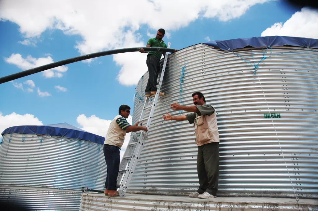 Aid workers fill a large water tank